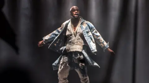 Getty Images Kanye West with his arms outstretched on the stage at Glastonbury in 2015