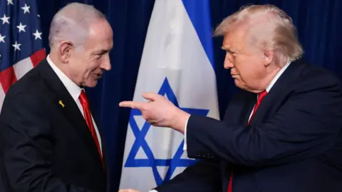US President Donald Trump (R) points his finger towards Israeli Prime Minister Benjamin Netanyahu (L) as they shake hands during a press conference at Mar-a-Lago, in Palm Beach, Florida (29 December 2025)