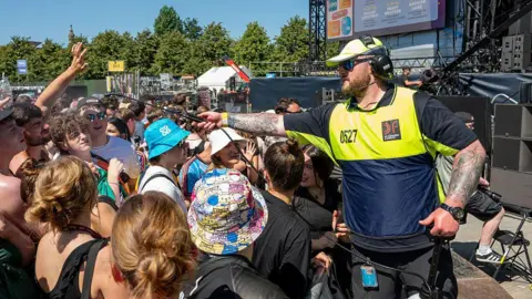 Getty Images A steward sprays music fans with water during a music festival