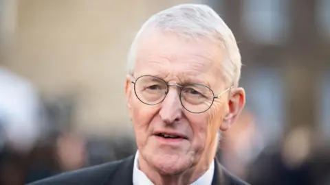 PA Media Hilary Benn, a man with grey hair and spectacles, wearing dark suit and white shirt.