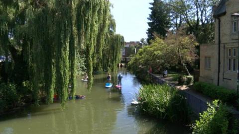 A group of volunteers using stand up paddleboards on Oxford's canal