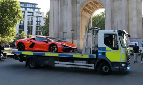 Met Police An orange Lamborghini supercar on a Metropolitan Police flatbed recovery truck beside Wellington Arch