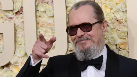 Gary Oldman in a dinner jacket on the red carpet at the Golden Globe Awards in January, pointing off camera