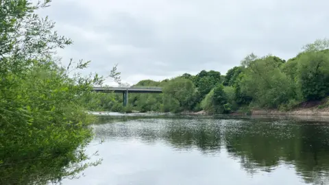 PA Bridge over a broad swathe of river with greenery on the banks