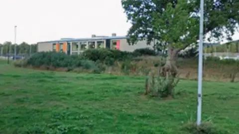 A view across a grassy area towards the school. 