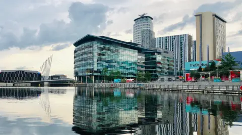 MediaCityUK at Salford Quays features large office buildings, broadcast studios, bars and restaurants next to the Manchester Ship Canal.