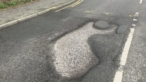 A close up of a large pothole in the road