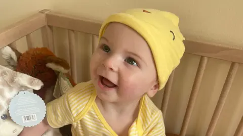 Family handout A young boy in a yellow stripey shirt and hat smiles at the camera