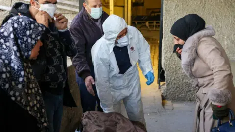 AFP A woman covers her mouth while viewing the body of a man in a Damascus hospital, after rebels said they found about 40 people showing signs of torture in Harasta Hospital (December 10, 2024)