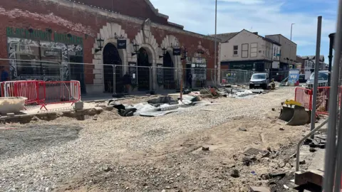 Roadworks on King Street in Southport where the road in completely fenced off and tramac has been removed. Two vans can be seen parked in the distance.