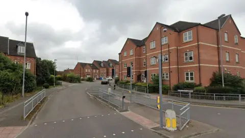 Google Streetview image of a modern housing estate with individual houses and a block of apartments