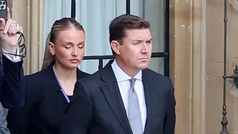 James Roscoe at Windsor Castle wearing a black suit, grey tie and white shirt