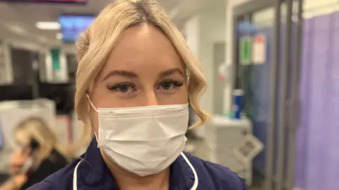 A face-masked nurse in uniform in a hospital 