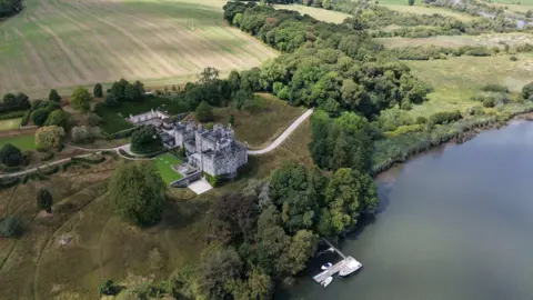 Reuters An aerial view of a castle, surrounded by trees and fields. It is overlooking a river. There is a boat on the river.