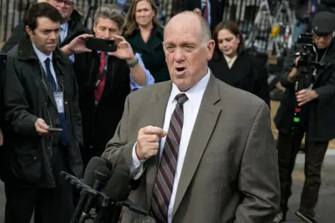 Getty Images Tom Homan dressed in a suit speaks to reporters outside the White House