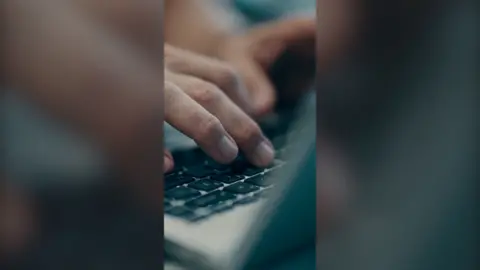 Fingers typing on a laptop keyboard