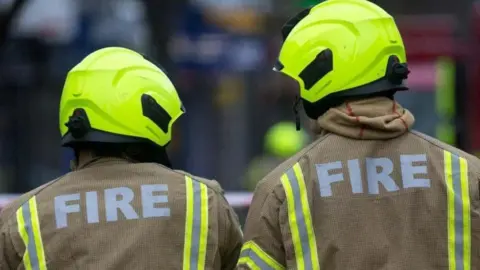 Two firefighters with their backs to the camera