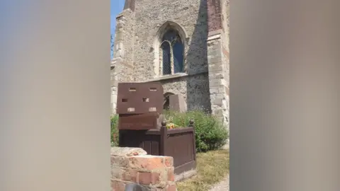 Essex Swift Recovery Project Wooden nesting boxes positioned outside St Peter's Church in Maldon, sitting on top of a flower bed