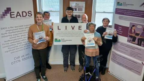 Six people of varying ages pose for a photo and hold up signage for the LIVE scheme.