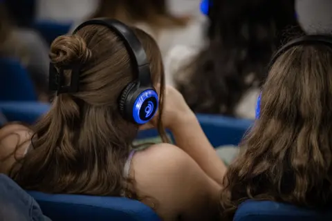 A girl is wearing a pair of headphones which is part of the breathwork technique