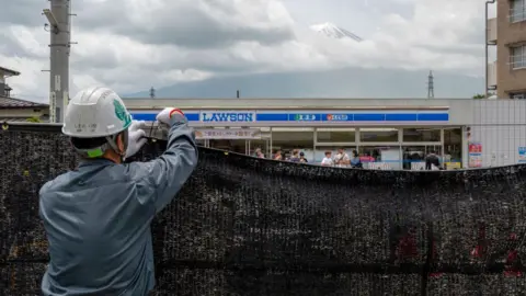 Getty Images A worker installs a barrier to block the sight of Japan's Mount Fuji