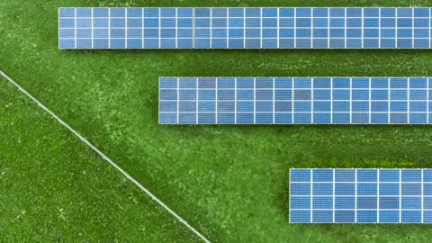 Solar farm panels parallel to eachother in a grassy field