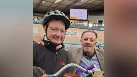 Mel Glass Two men taking a selfie in a velodrome