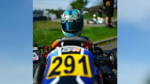 Supplied A close-up photo of Jack Collinson, in a helmet, sitting in a blue racing kart with the number 291 on the front.