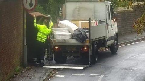 A council worker removes fly-tipped rubbish from a pavement