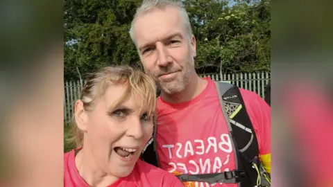 Joanne Graham A man and a woman dressed in pink sports shirts pose together smiling at the camera