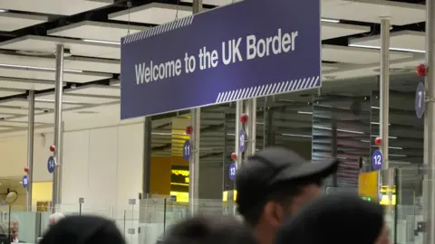 BBC Welcome to the UK signage at UK Border Force check-in desks at Gatwick Airport