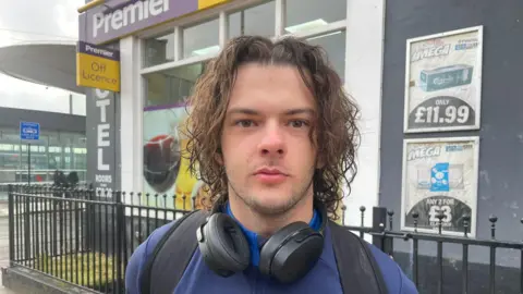 Wyatt Bennett - a man with wavy brown hair and earphones around his neck looks directly into the camera