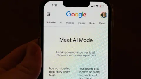 A person holding a phone with Google "AI Mode" on the screen