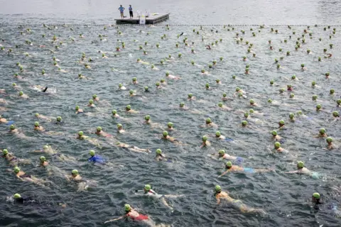 Michael Buholzer / EPA-EFE Swimmers cross Lake Zurich