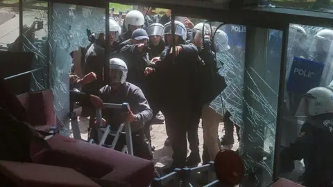 Riot police fire tear gas as they break the entrance door of the party’s headquarters on May 24, 2026 in Ankara, Turkey.