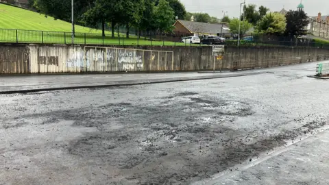a road surface damaged by fire. Scroch marks and indents are seen on a road surface.