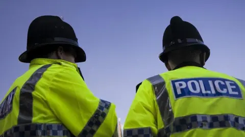 AFP via Getty Images Two police officers stood looking away from the camera. 