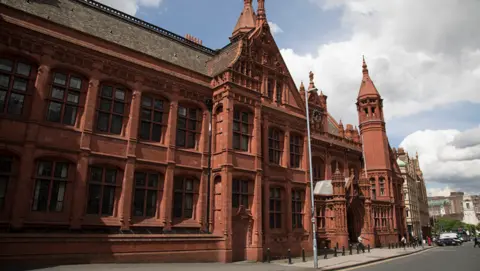 The front of Birmingham Magistrates' Court - a red brick building with a clock on the outside and windows over two floors.

