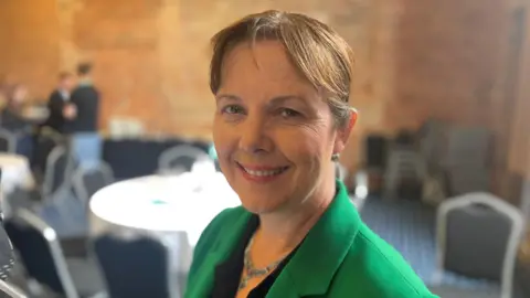 A close-up photo of Claire Ward. She's wearing a green blazer.