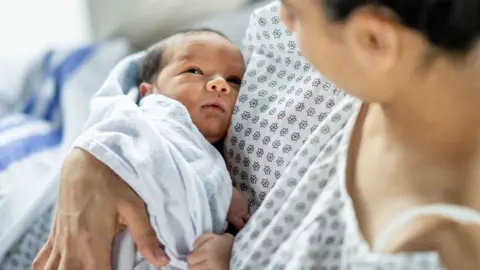 A mother holds her newborn baby in hospital