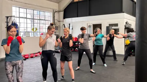 Lily-May Symonds/BBC Women learnign how to box in a line inside a club