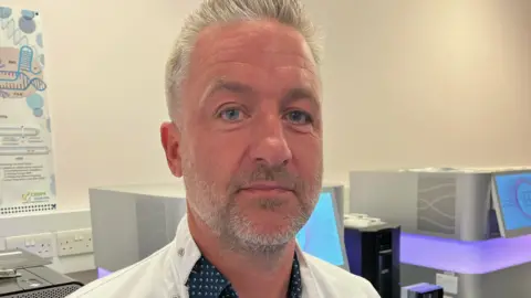Prof Jim Wilson in his research lab, wearing a white coat