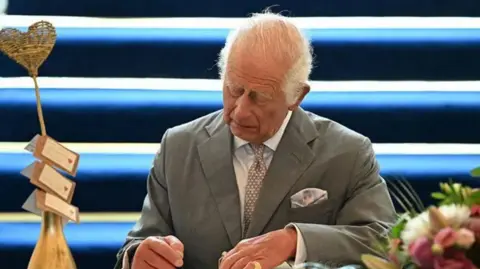 Reuters King Charles signing a book of condolence for the three girls killed in a knife attack