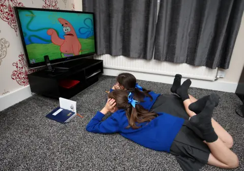 PA Two girls lying on the floor watching television