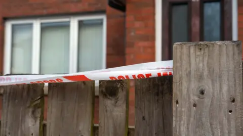 Red and white police tape on a fence in front of a house in the Corban Avenue area of Enniskillen.