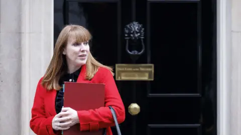 EPA Deputy Prime Minister Angela Rayner wearing a black top and a red coat and holding a file outside 10 Downing Street