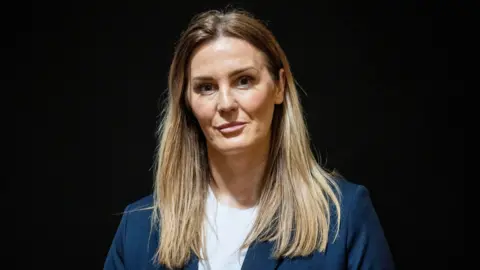 Liam McBurney/PA Then UUP candidate Linzi McLaren during the party's local government manifesto 2023 launch at the Linen Hall Library, Belfast. She has long blonde hair and a navy jacket with white t-shirt on underneath 