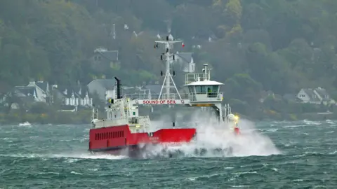 Michael Deveney, BBC Weather Watchers large waves hit bow of car ferry at sea, with houses and trees on shore in distance