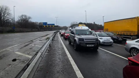 Caroline Thorne Stationary cars on a closed motorway on a wet and cloudy day.