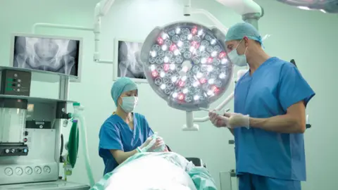 Getty Images Cirurgião ortopédico e enfermeiro preparando paciente para cirurgia de quadril em centro cirúrgico - foto de stock